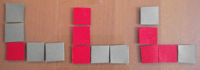 Description : photographie, trois présentations de l’étape 3, le carré initial est rouge. À gauche : les quatre carrés ajoutés sont gris ; au milieu : les deux carrés ajoutés en haut sont rouges, ceux à droite gris ; à droite : les premiers carrés ajoutés en haut et à droite sont rouges, les suivants en gris.