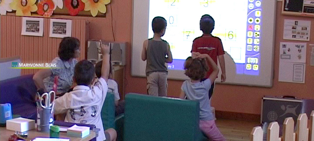 Des élèves de maternelle font un travail collaboratif sur le TBI en présence de leur enseignante, Maryvonne Blais.